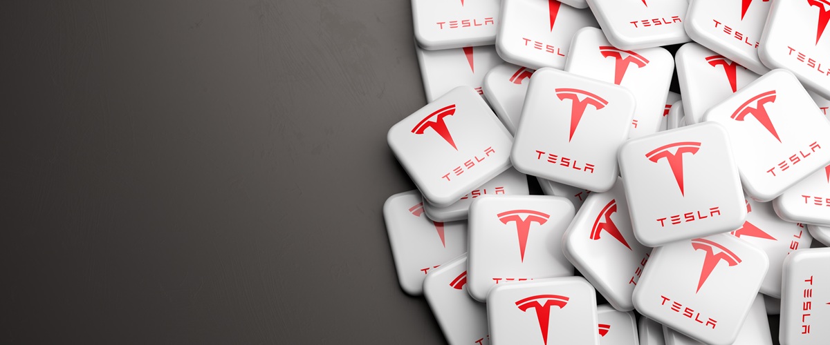 3D render of scattered Tesla logo tiles on a clean gray background. Concept image for electric vehicles, EV technology, automotive innovation, energy and future mobility themes.
